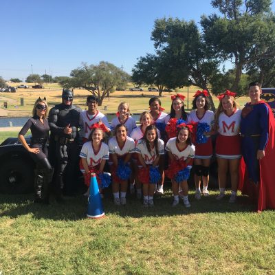 Lubbock Batman, superman pose with the Monterey Cheerleaders
